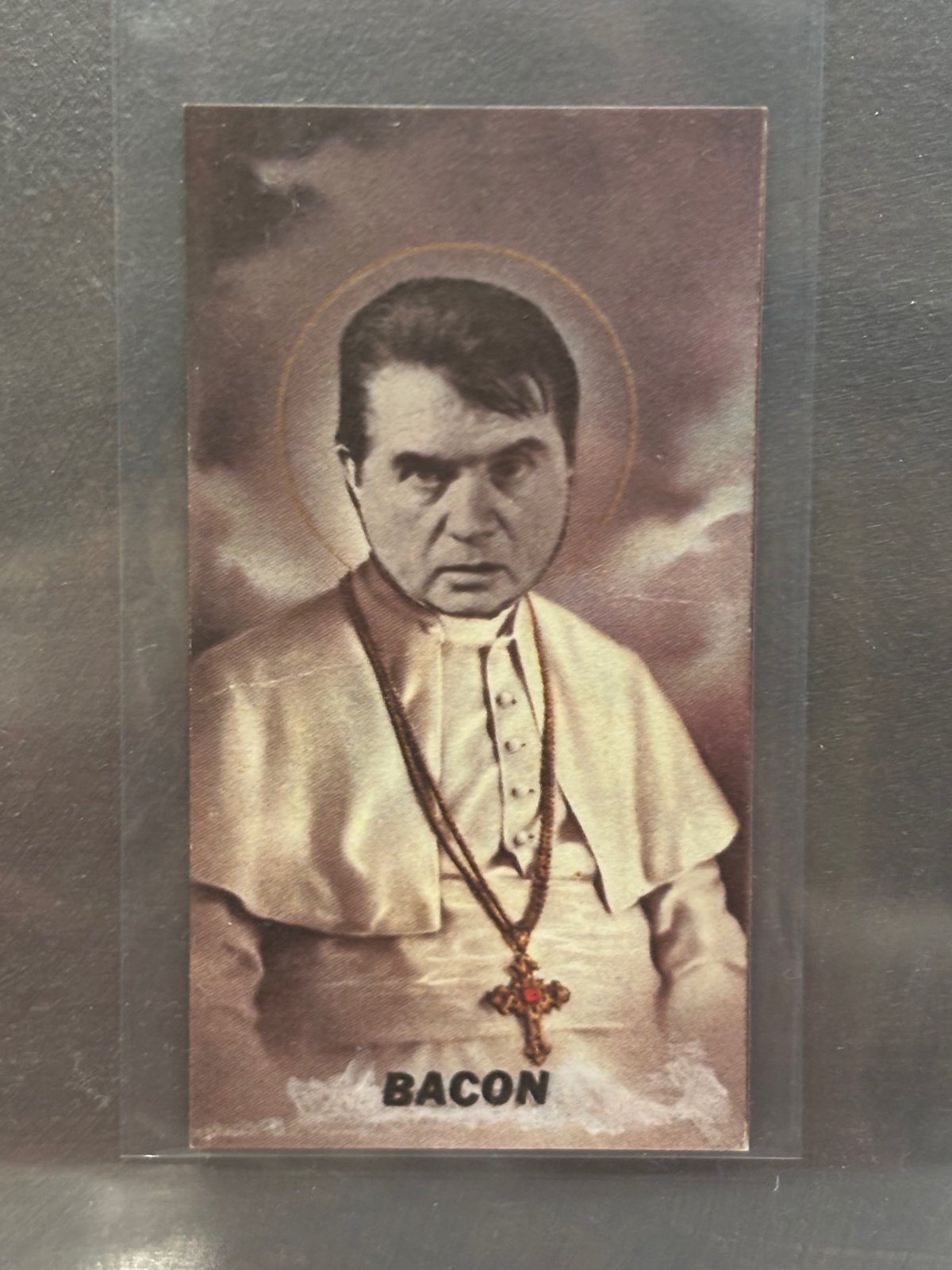 Holy Holy Art Card of Francis Bacon as a pope, with a gold halo and pectoral cross, captioned "BACON."