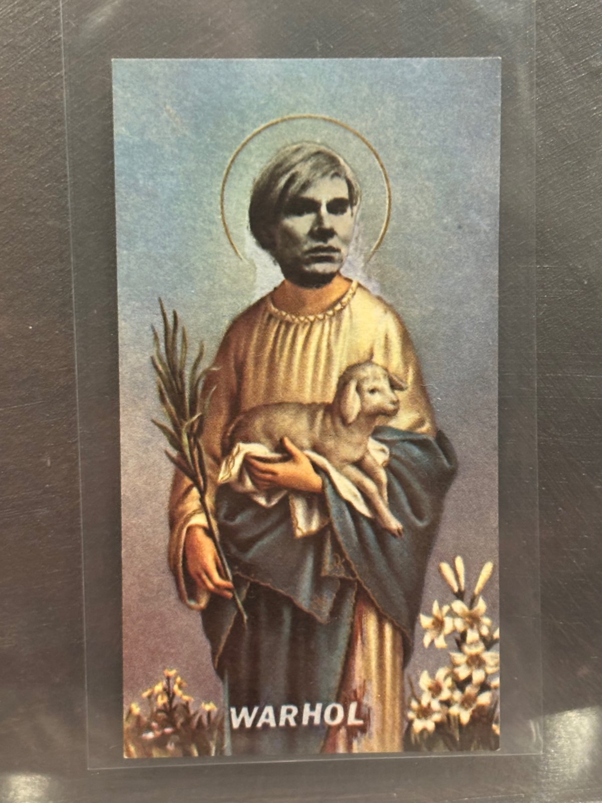 Holy Holy Art Card of Andy Warhol as a haloed young saint holding a lamb and a palm frond, captioned "WARHOL."